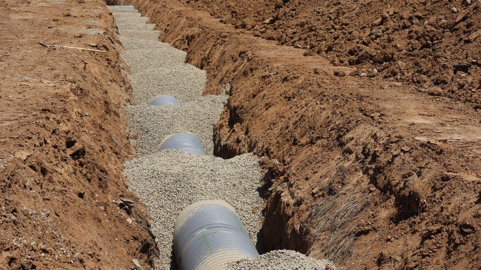 New perimeter drain tile bedded in clean drain rock along a foundation